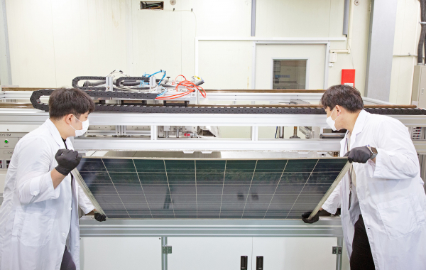 연구원들이 유리를 분리·회수하기 위해 태양광 폐패널을 개발 장치에 넣고 있다.